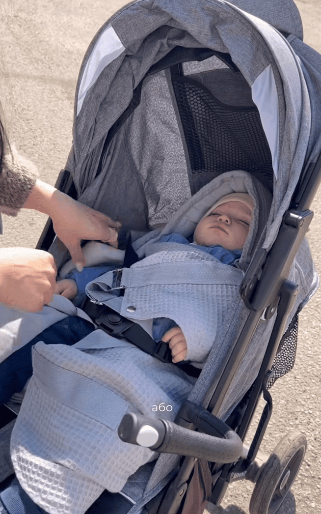Baby napping outside in a stroller while wrapped comfortably in the KESLOVE carrier.