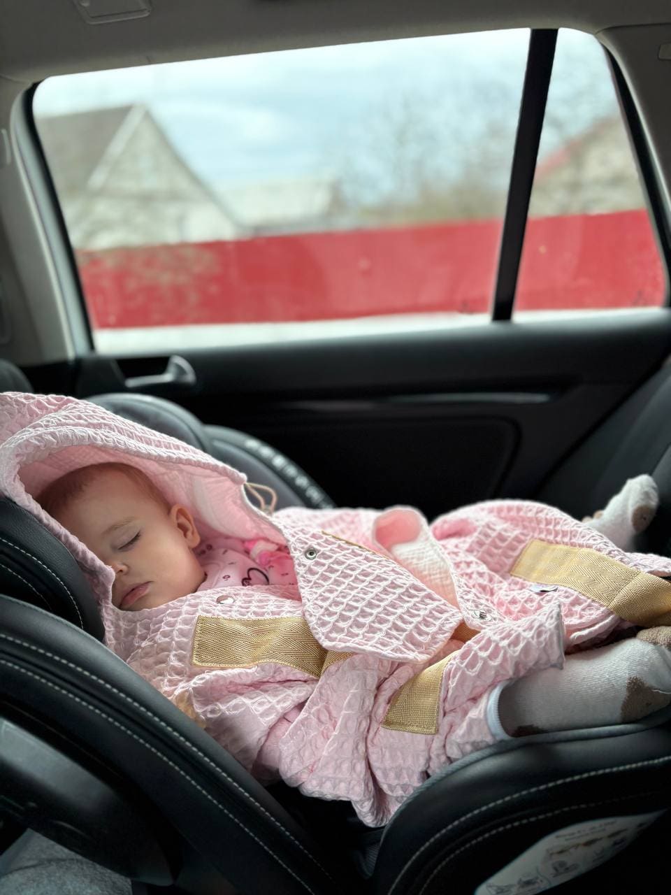 Sleeping baby tucked into the KESLOVE carrier inside a car seat for a silent and seamless transfer.