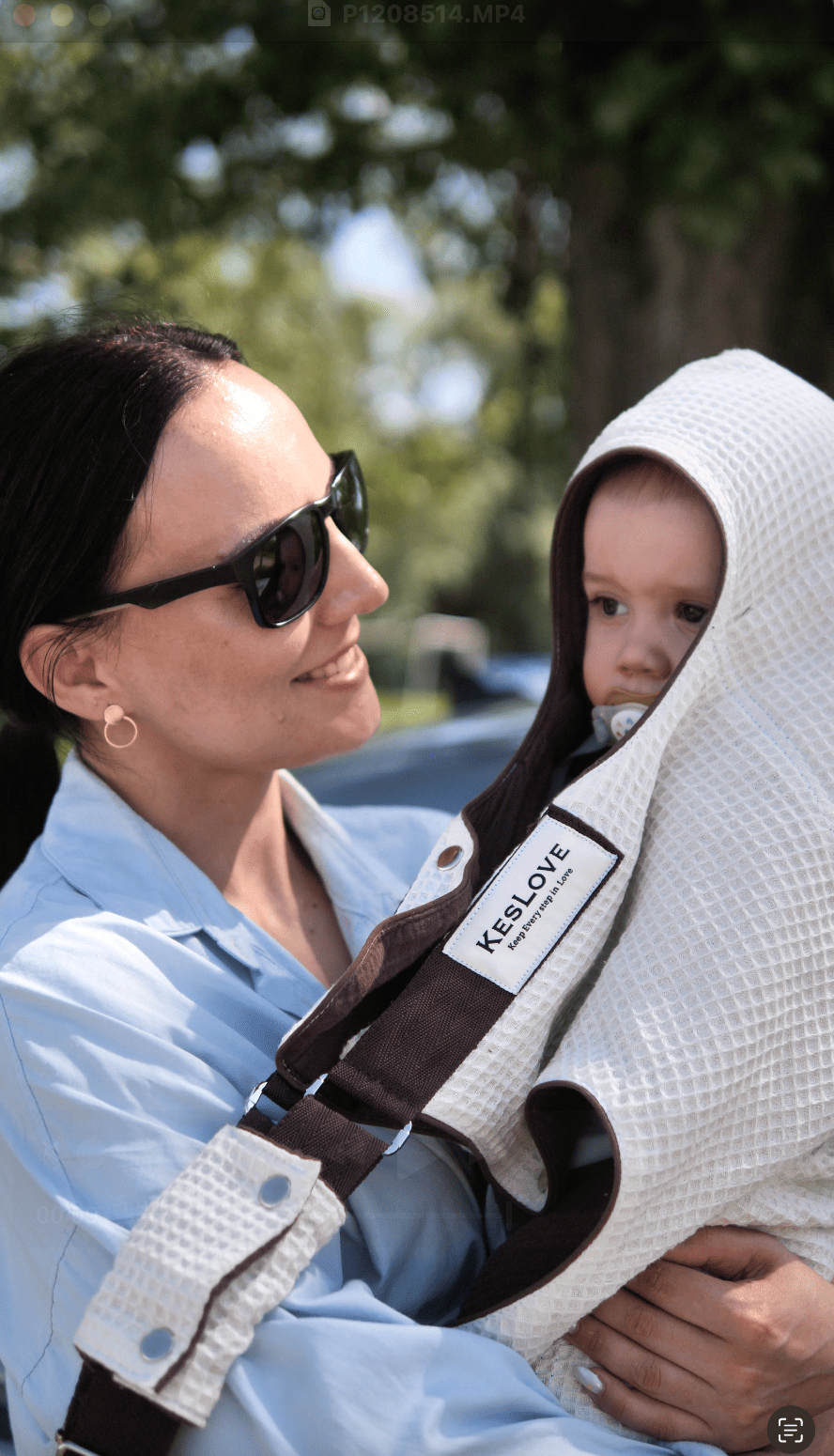 Mother holding her baby close in a KESLOVE ergonomic carrier while pushing a stroller, enjoying freedom and comfort.