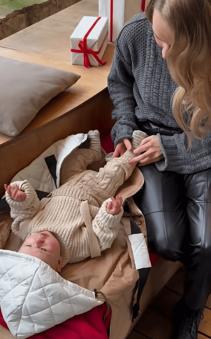 Mom cuddling a napping baby secured comfortably in the KESLOVE natural cotton carrier.